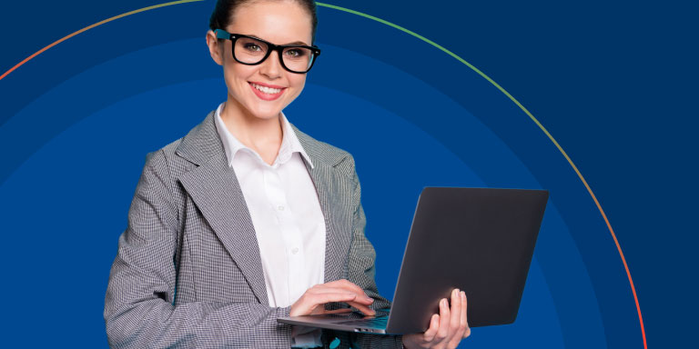 A female stock analyst wearing glasses, a grey blazer and white shirt, while holding a laptop.