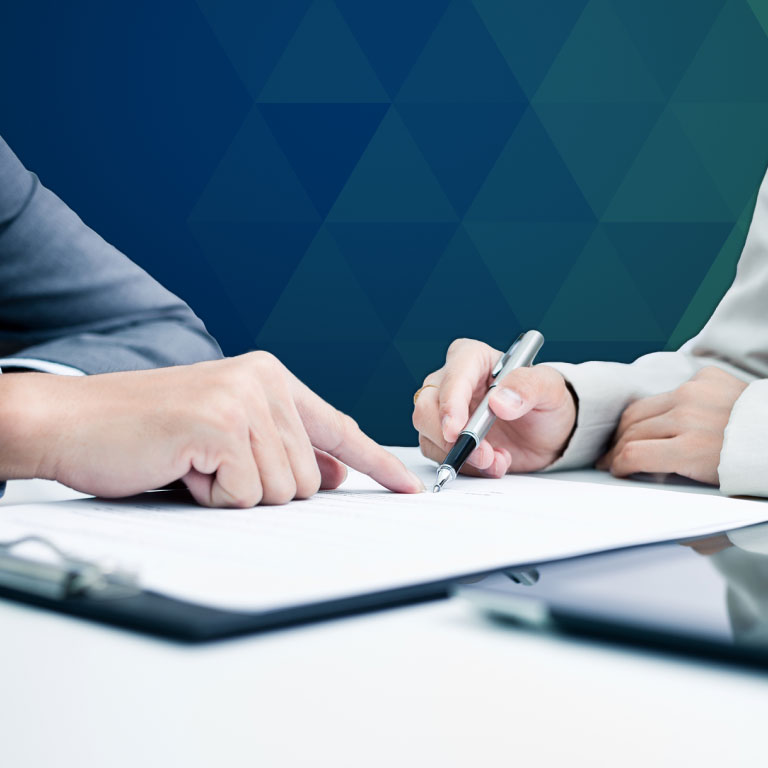 A financial adviser and a client pointing at and writing on a notepad.